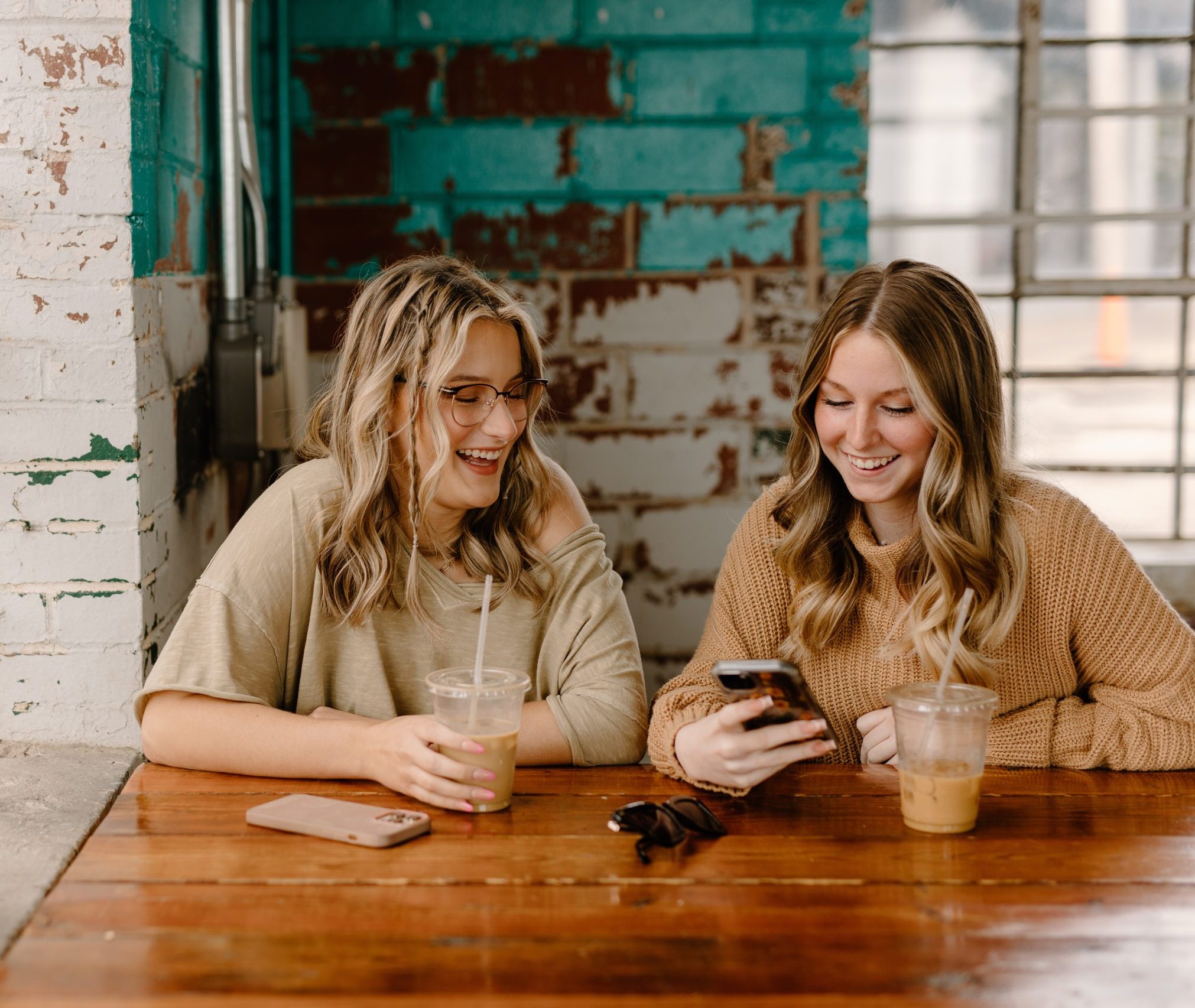 Two women sitting at a table looking at their phones.